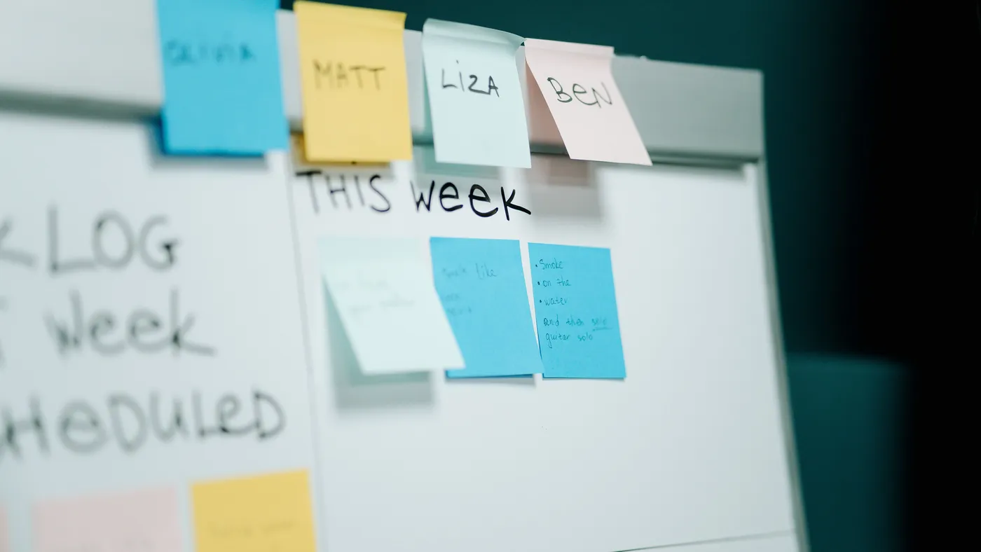 A whiteboard covered in rows of colorful sticky notes used to plan and order tasks