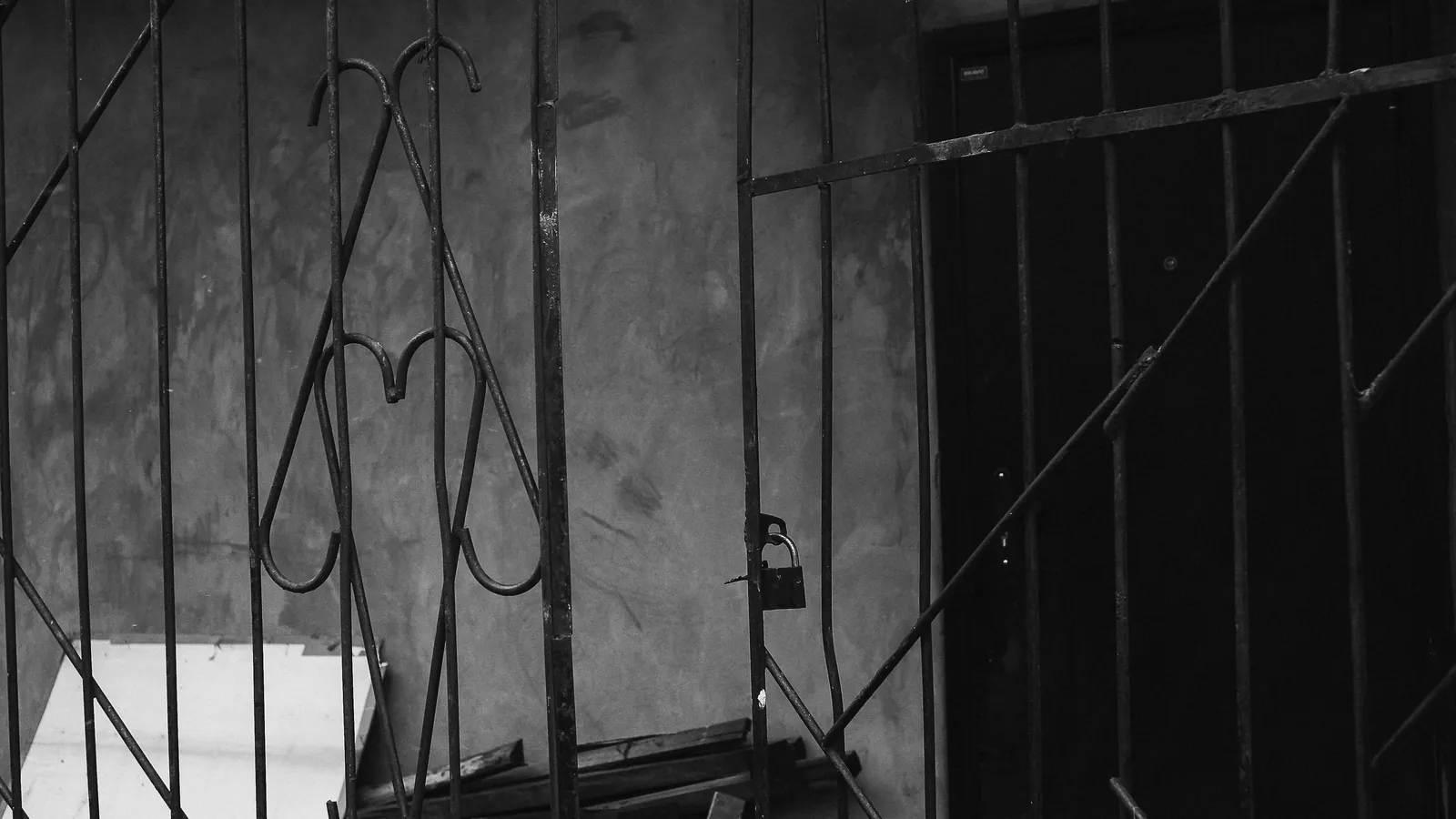 A metal gate standing open with a padlock still fastened to the frame