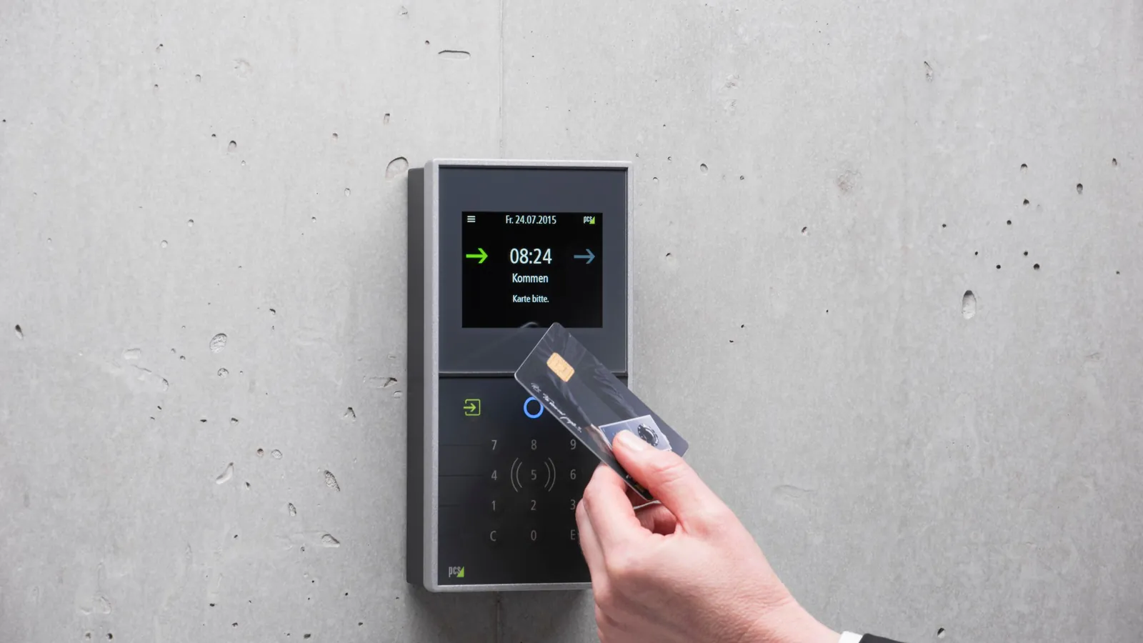 A man holding an access card up to a card reader mounted on a concrete wall