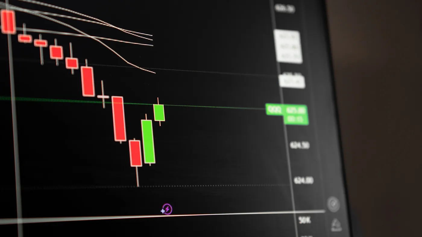 A candlestick trading chart on a dark screen showing a sustained downward price trend