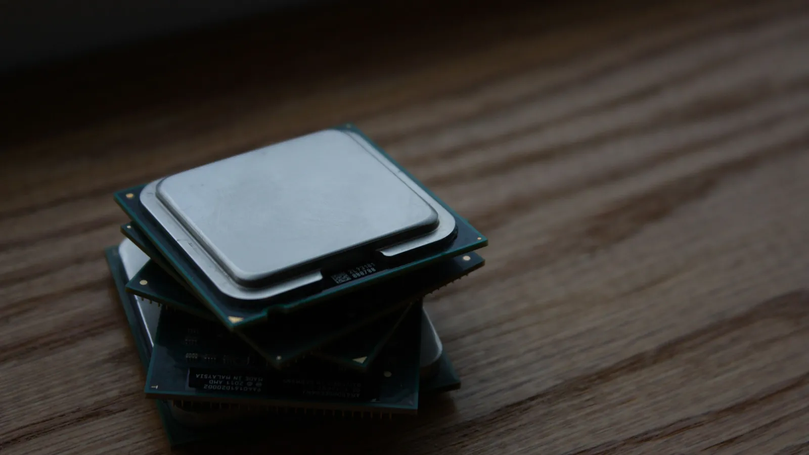 A pile of identical computer processors stacked on a wooden surface